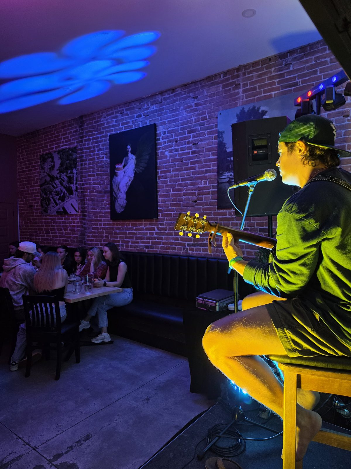 Acoustic musician performing on stage in front of a brick wall